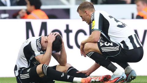 Dan Burn consoles Tino Livramento after he suffered a knee injury in Newcastle United's defeat against Arsenal