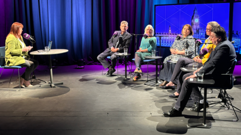 The debate was set up with the presenter Steph Finnon on the left. She's sitting down, with her laptop in front of her and is speaking into a 鶹ҳ Radio Cumbria microphone. The five politicians taking part in the debate are sitting opposite her.