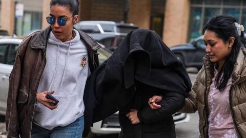 Elmina Aghayeva seen under a jacket being led away by agents