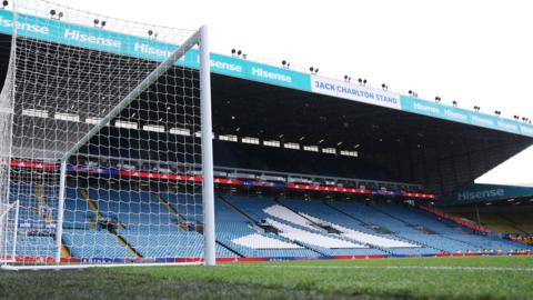 A view of an empty Elland Road from the pitch. Lots of blue and white seats can be seen. 