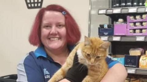 Raymond the ginger cat with Aldi shop worker Lara Milne