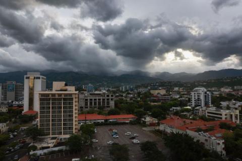Storm clouds hover over the mountains as people make last-minute preparations for the arrival of Hurricane Beryl in Kingston, Jamaica