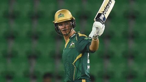 Josh Philippe in green Multan Sultans kit and gold helmet raises bat towards crowd