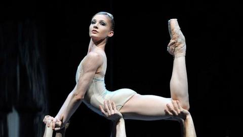 Melissa Hamilton posing in a ballet outfit, lifted into the air by three sets of hands