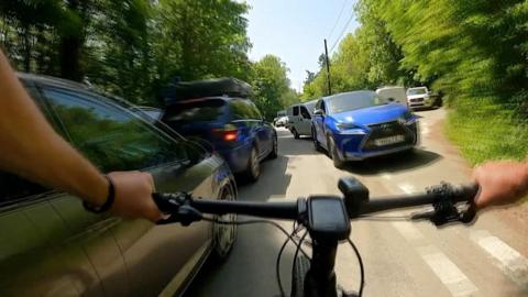 A bike weaving through cars on either side of the road