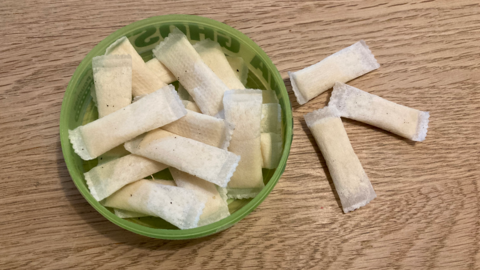 Nicotine pouches in a tub. They are small and white and wrapped in paper.