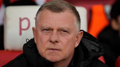 Stoke City manager Mark Robins looks pensive as he sits on the bench during a game in April 