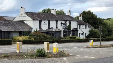 A pub with white rendering and a grey slate roof positioned next to a dual carriageway.