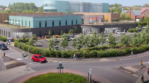 Artist's impression of what the centre will look like. It's a light blue, glass and wood building with a car park in front and is surrounded by trees, close to a main road