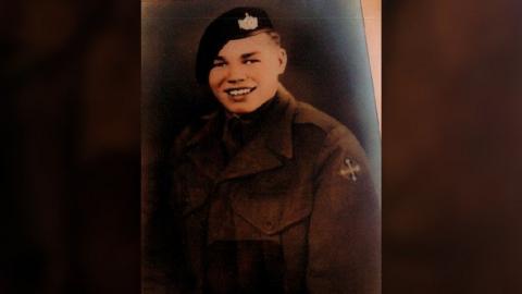 Roy Mills as a young man in military clothing, with a cap, smiling at the camera in a portrait-style photo