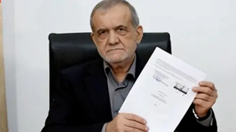  Iran’s President Masoud Pezeshkian holding a signed memorandum 
