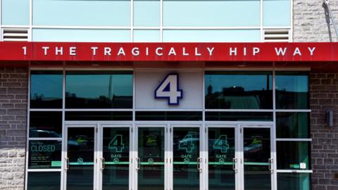 A building front with glass doors and a sign saying 1 The Tragically Hip Way.
