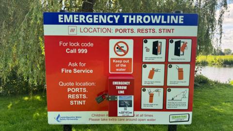 A red sign board with information on keeping out of the water and instructions for a throw line.