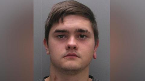 Mugshot of Fish. He has dark hair swept across his head and is clean shaven.