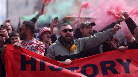 Manchester United fans protest with banners and flares