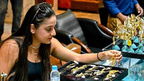 The image shows a woman wearing a sleeveless black top buying ornaments at a jewellery store in Amritsar in northern India.
