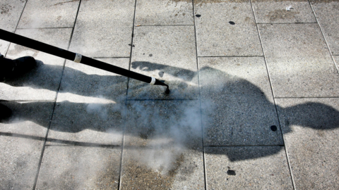 Gum being cleaned of the ground with a hose jet