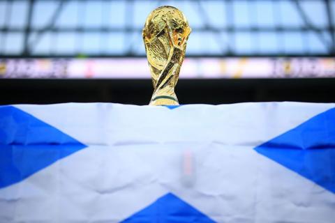 A World Cup trophy is perched on top of a Scotland flag.