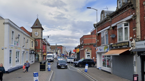 Google image of Regent Street in Kingswood. There are shops down either side of the road, with cars driving towards the camera. 