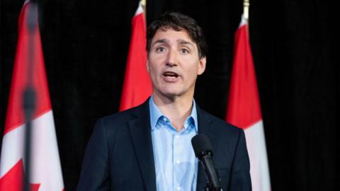 Justin Trudeau, Canada's prime minister, during a news conference at a cabinet retreat in Halifax, Nova Scotia, Canada, on Monday, Aug. 26, 2024, standing in front of a row of Canadian flags.