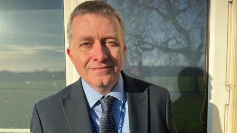 A man in a suit outside a school window