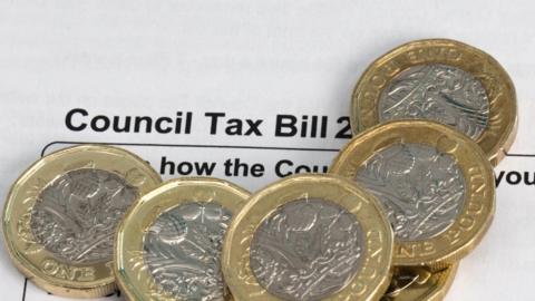 Six pound coins sitting on top of a council tax bill.