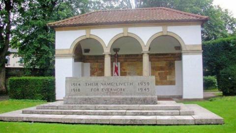 Stone of remembrance on a three-stepped base in front of names inscribed on interior wall