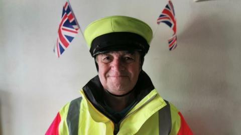 Dave York in lollipop man uniform has two union flags sticking out of his hat.