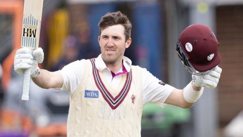 Somerset's Craig Overton raise his bat and helmet to celebrate scoring a centiry against Essex