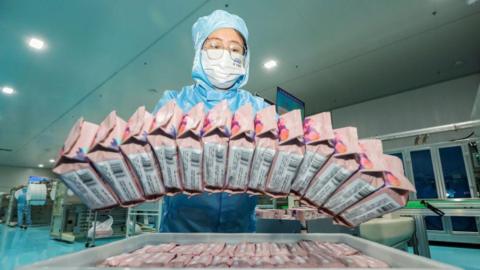 An employee works on the production line of sanitary napkins at a factory