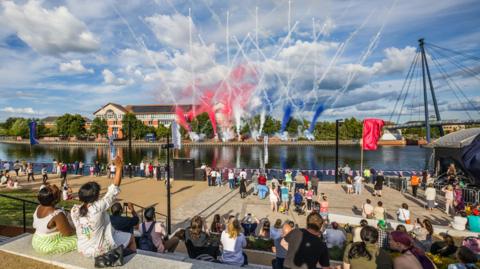 Crowds cheer from Stockton Waterfront's amphitheater as they watch a blue, red and white smoke display from the other side of the river Tees. 