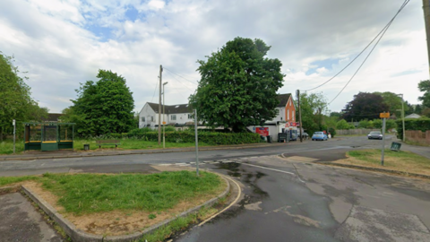 Road running through Oakley village with a shop and bus stop seen on the far side of the road.