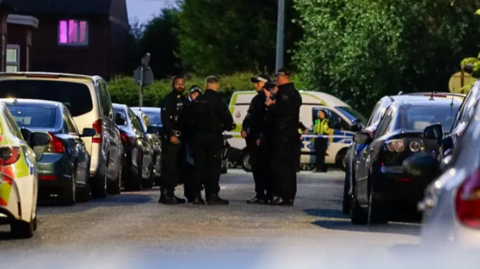 Police officers gather at the scene of the dog attack