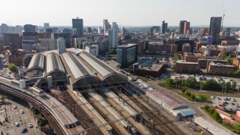 Aerial shot of Manchester Piccadilly train station with the city skyline in the background.