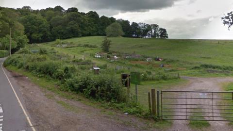 A large green space on the side of a country road.