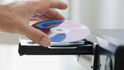 A man places a DVD disk into a DVD player