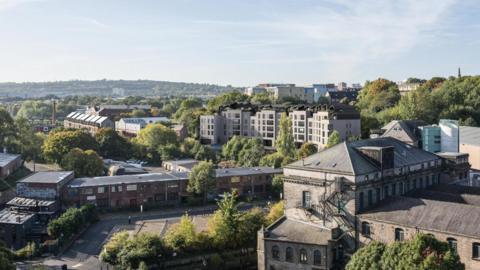 An artist's impression of what the flats would look like in the Ouseburn Valley. There are several large, grey buildings with large windows among the stone and brick buildings.