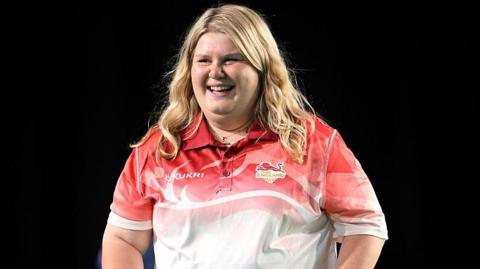A smiling Katherine Rednall in a red and white Team England jersey