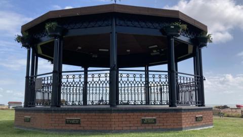 Deal bandstand with a blue sky and light clouds in the background. 