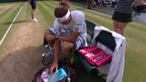 Alexander Zverev checks his insulin levels on his phone during a match at Wimbledon