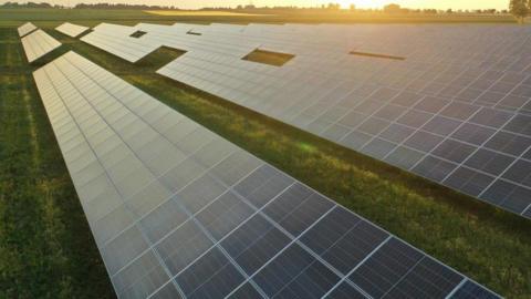 A solar farm with a sun setting in the background