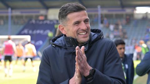 John Mousinho smiles and rubs his hands together
