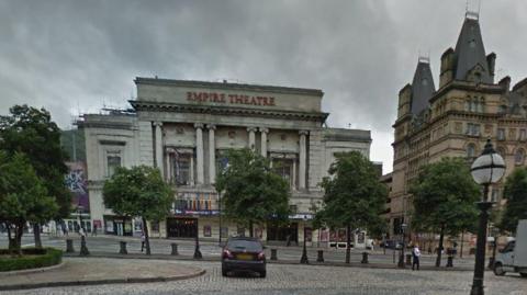 Liverpool's Empire theatre, seen from outside St George's Hall. The theatre is a neo-classical structure with six ionic columns beneath a large red sign saying Empire Theatre. 