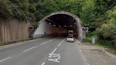 A picture of a large tunnel. There is a car and lorry traveling in it.