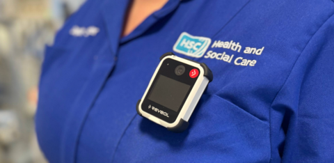 Close shot of a body camera on a blue Health and Social Care uniform top