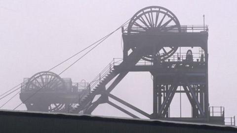 The pit bank or brow at the top of the colliery.  Wheels are visible and the top of the shaft.