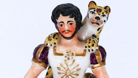 A ceramic figure of a bearded man with a leopard round his neck