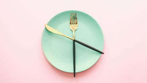 An empty plate with knife and fork across it, together it looks slightly like a clock.