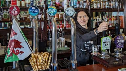 Vladyslava Krapyvka behind the bar of The Lamb pub 