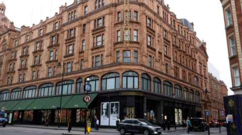 A general view of the Harrods department store in London. The building has the famous grand red bricks and green canopy draping over the pavements. A car can be seen driving past along Cromwell Road.